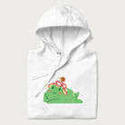 Folded white hoodie with a cottagecore design of a green frog wearing a mushroom cap and a snail on top.
