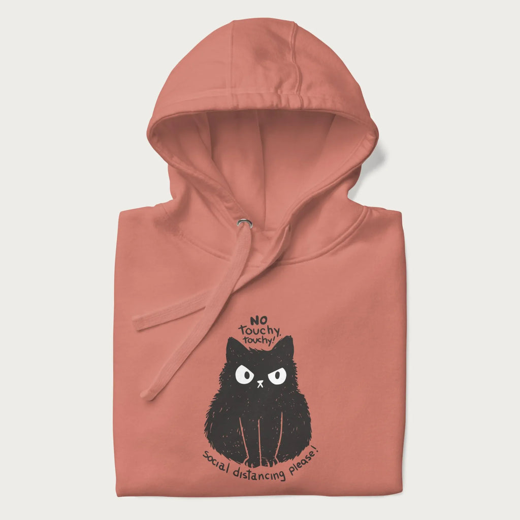 Folded light pink hoodie with a 'No Touchy, Touchy! Social Distancing Please!' black cat graphic design.
