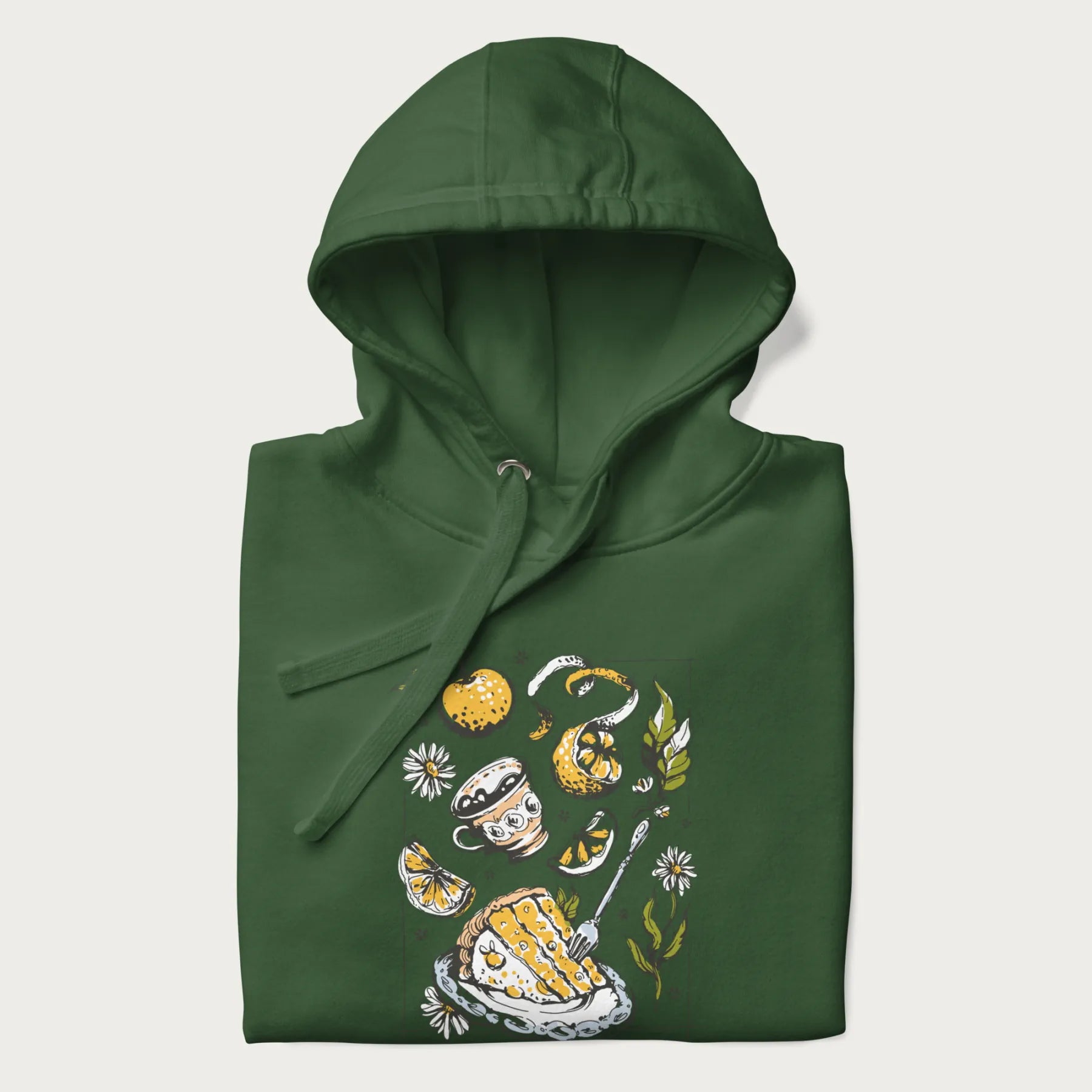 Folded forest green hoodie featuring a Cottagecore-themed graphic with oranges, a floral porcelain cup, orange pie, and daisies.