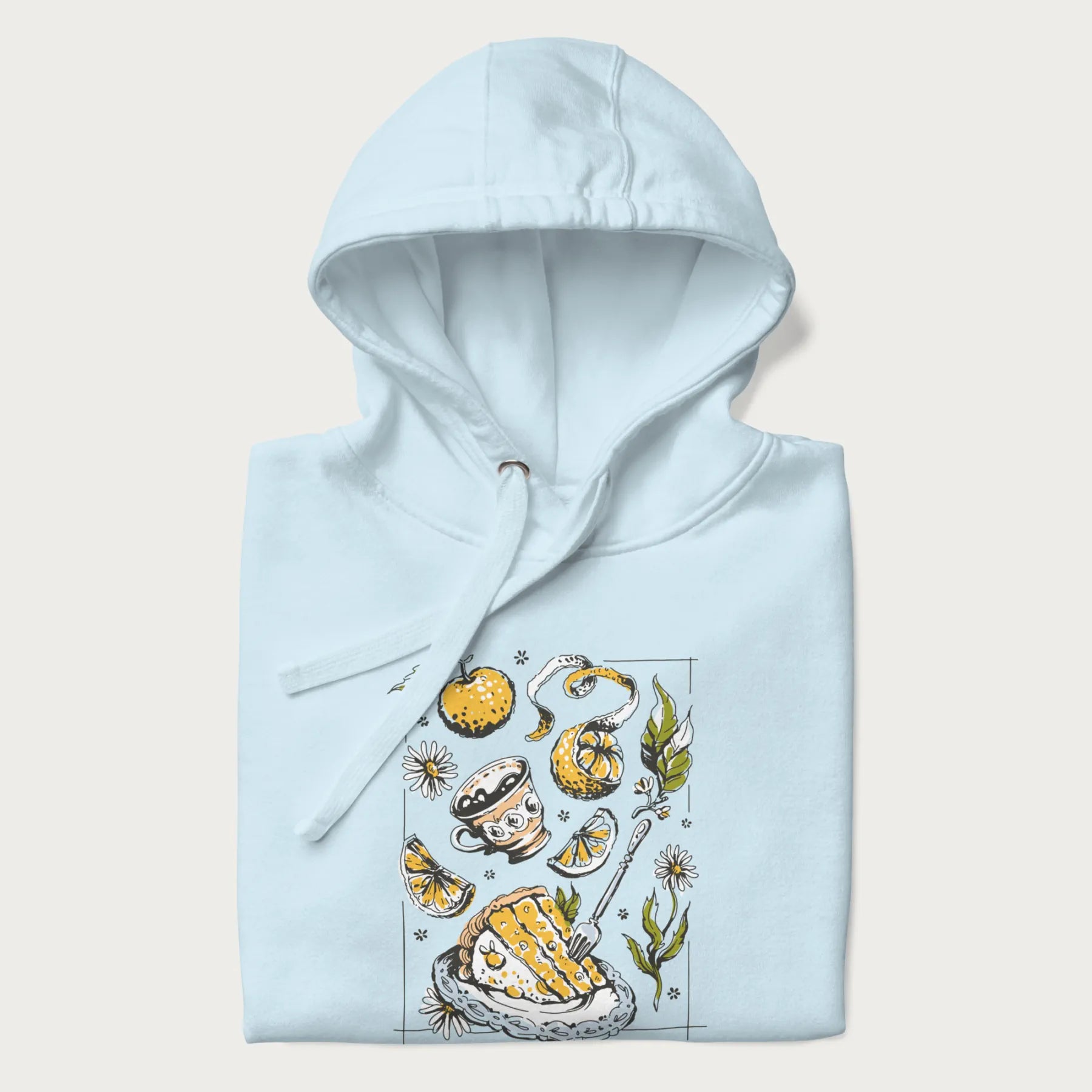 Folded light blue hoodie featuring a Cottagecore-themed graphic with oranges, a floral porcelain cup, orange pie, and daisies.