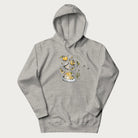 Light grey hoodie featuring a Cottagecore-themed graphic with oranges, a floral porcelain cup, orange pie, and daisies.
