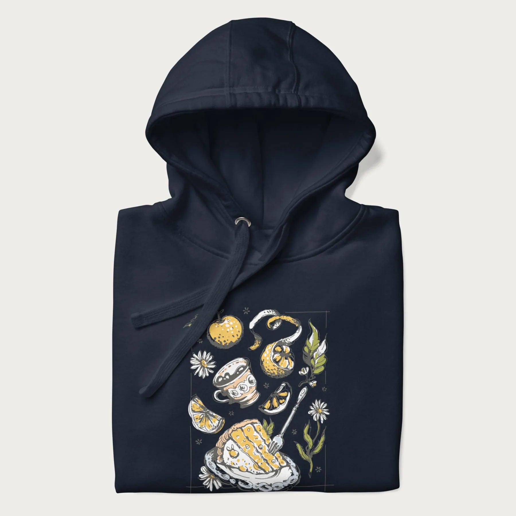 Folded navy blue hoodie featuring a Cottagecore-themed graphic with oranges, a floral porcelain cup, orange pie, and daisies.