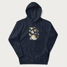 Navy blue hoodie featuring a Cottagecore-themed graphic with oranges, a floral porcelain cup, orange pie, and daisies.
