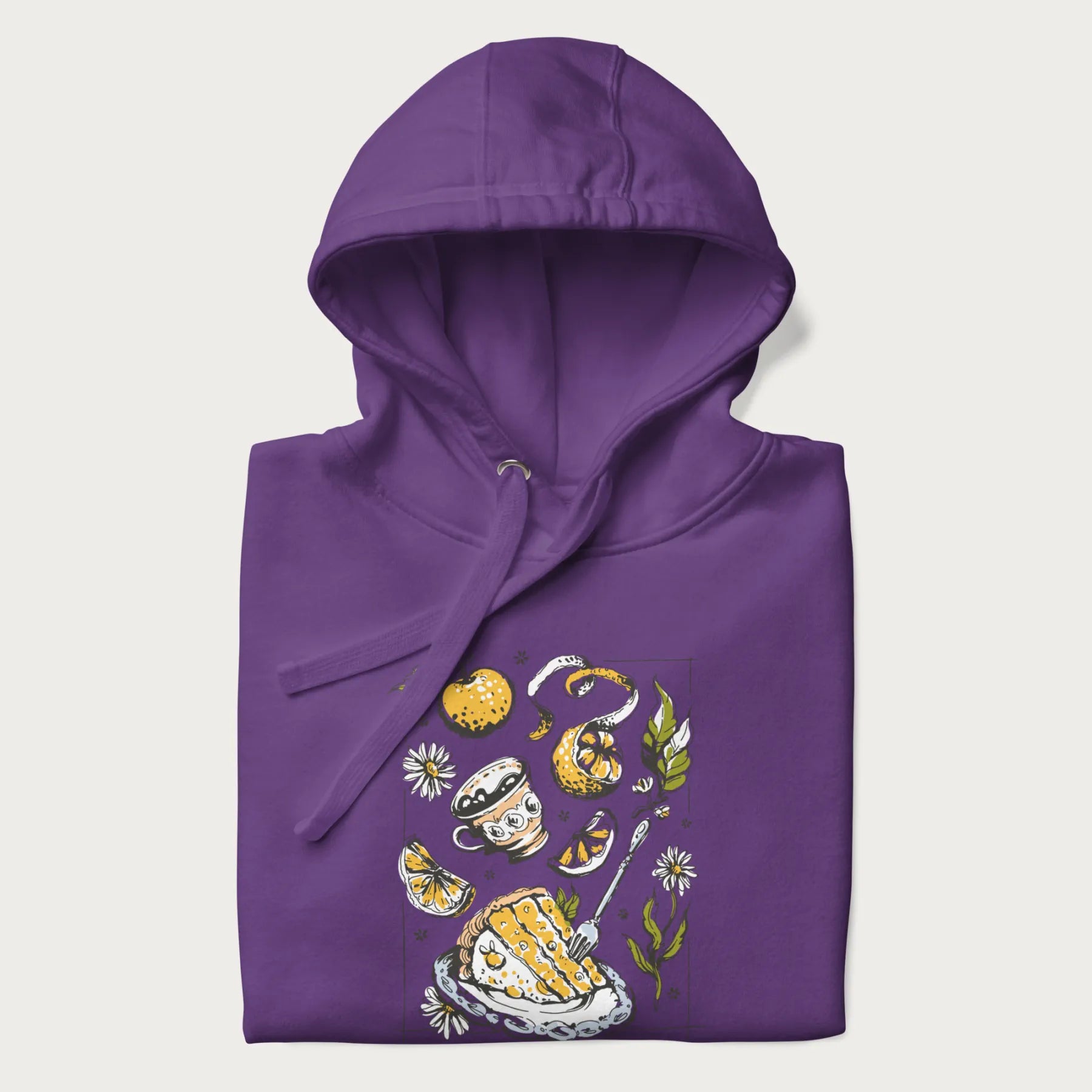 Folded purple hoodie featuring a Cottagecore-themed graphic with oranges, a floral porcelain cup, orange pie, and daisies.