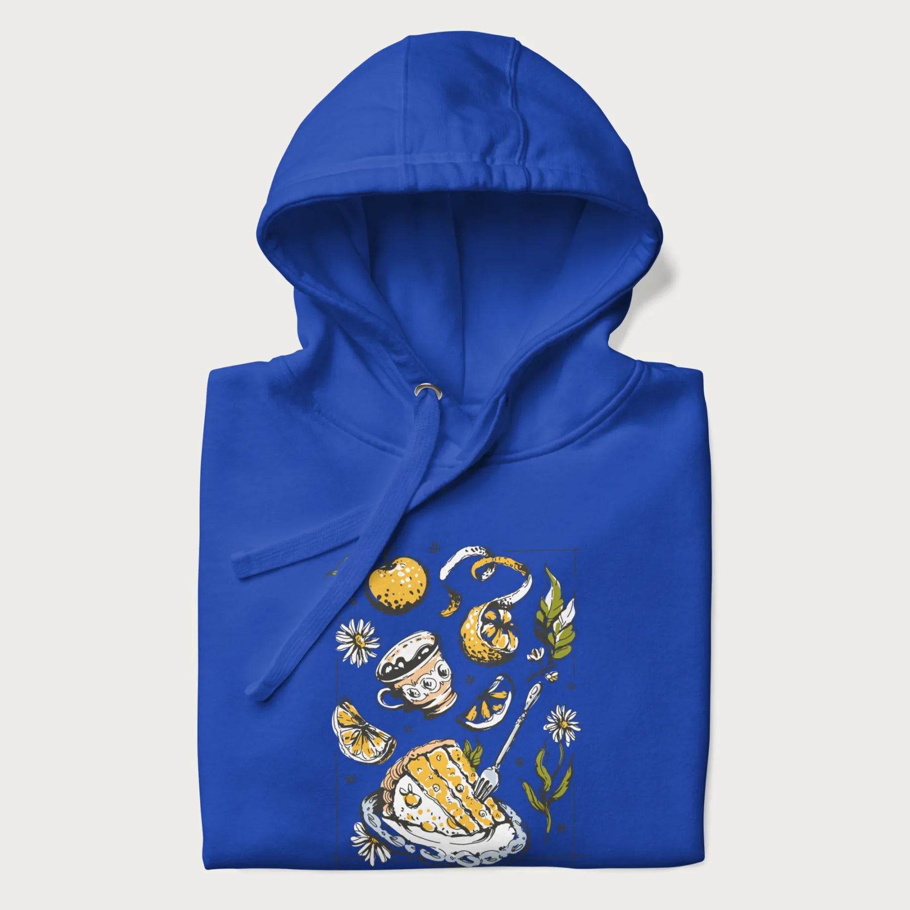Folded royal blue hoodie featuring a Cottagecore-themed graphic with oranges, a floral porcelain cup, orange pie, and daisies.