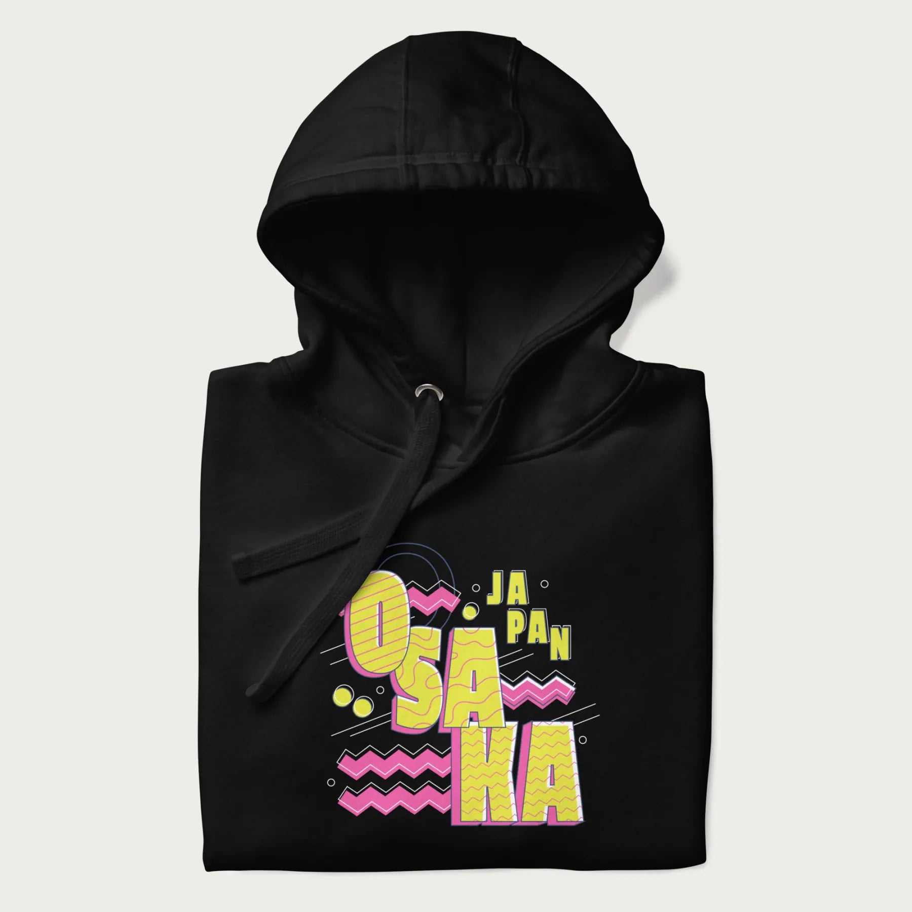 Folded black hoodie featuring a colorful 'OSAKA JAPAN' pop art design in bold pink and yellow, with abstract geometric shapes.