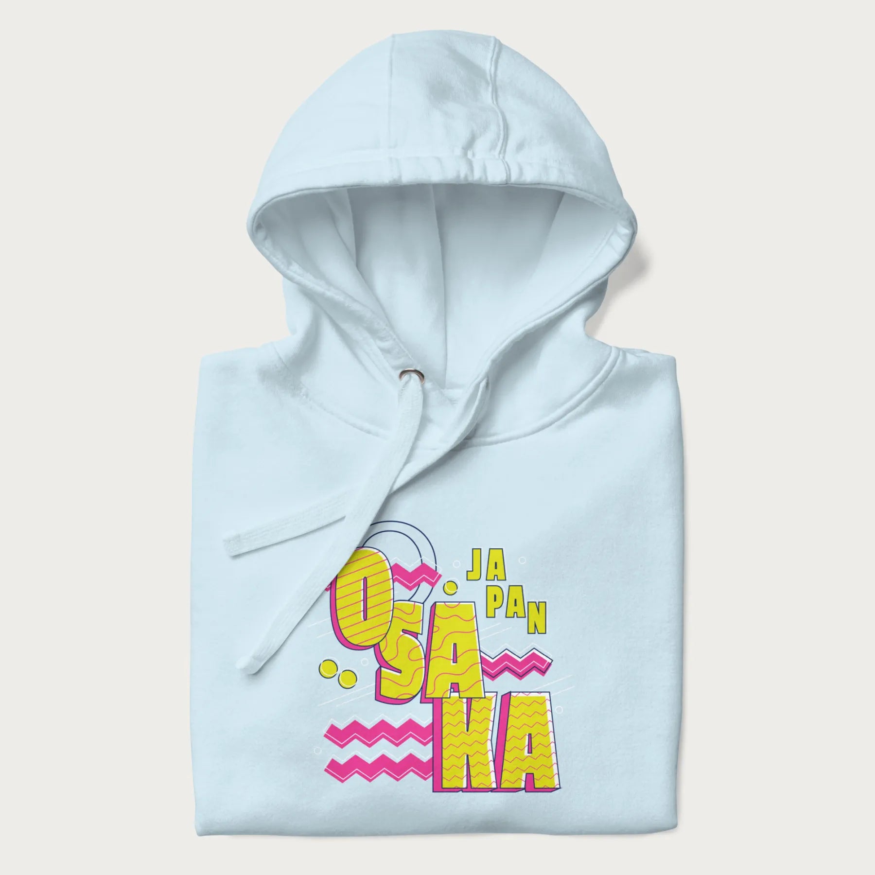 Folded light blue hoodie featuring a colorful 'OSAKA JAPAN' pop art design in bold pink and yellow, with abstract geometric shapes.