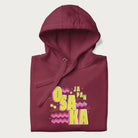 Folded maroon hoodie featuring a colorful 'OSAKA JAPAN' pop art design in bold pink and yellow, with abstract geometric shapes.