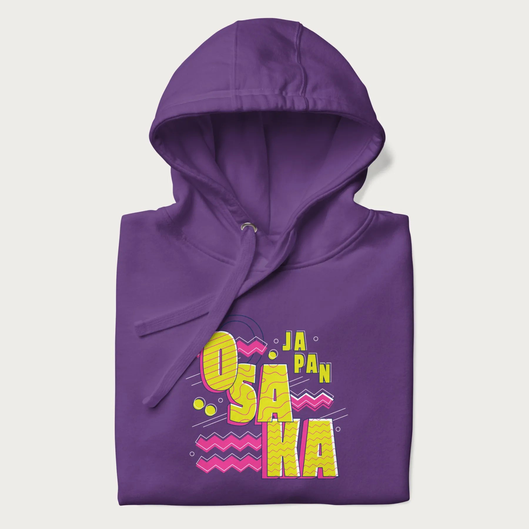 Folded purple hoodie featuring a colorful 'OSAKA JAPAN' pop art design in bold pink and yellow, with abstract geometric shapes.