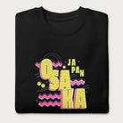 Folded black sweatshirt with a vibrant graphic of the words "OSAKA JAPAN" in large yellow letters, surrounded by pink zigzag lines.