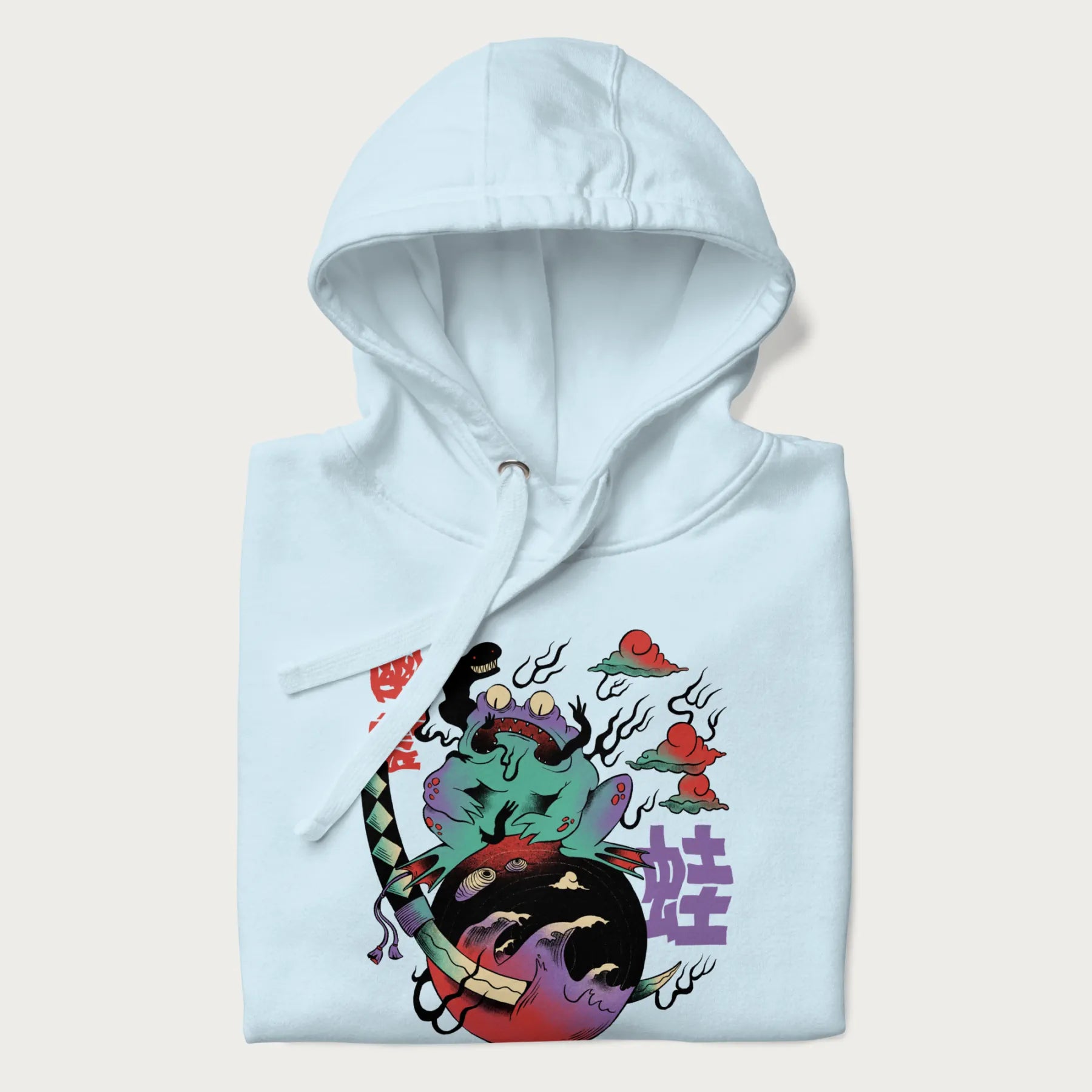 Folded light blue hoodie with Japanese psychedelic graphic of a frog with text '蛙' (Frog) and '幽靈' (Ghost) in Japanese characters.