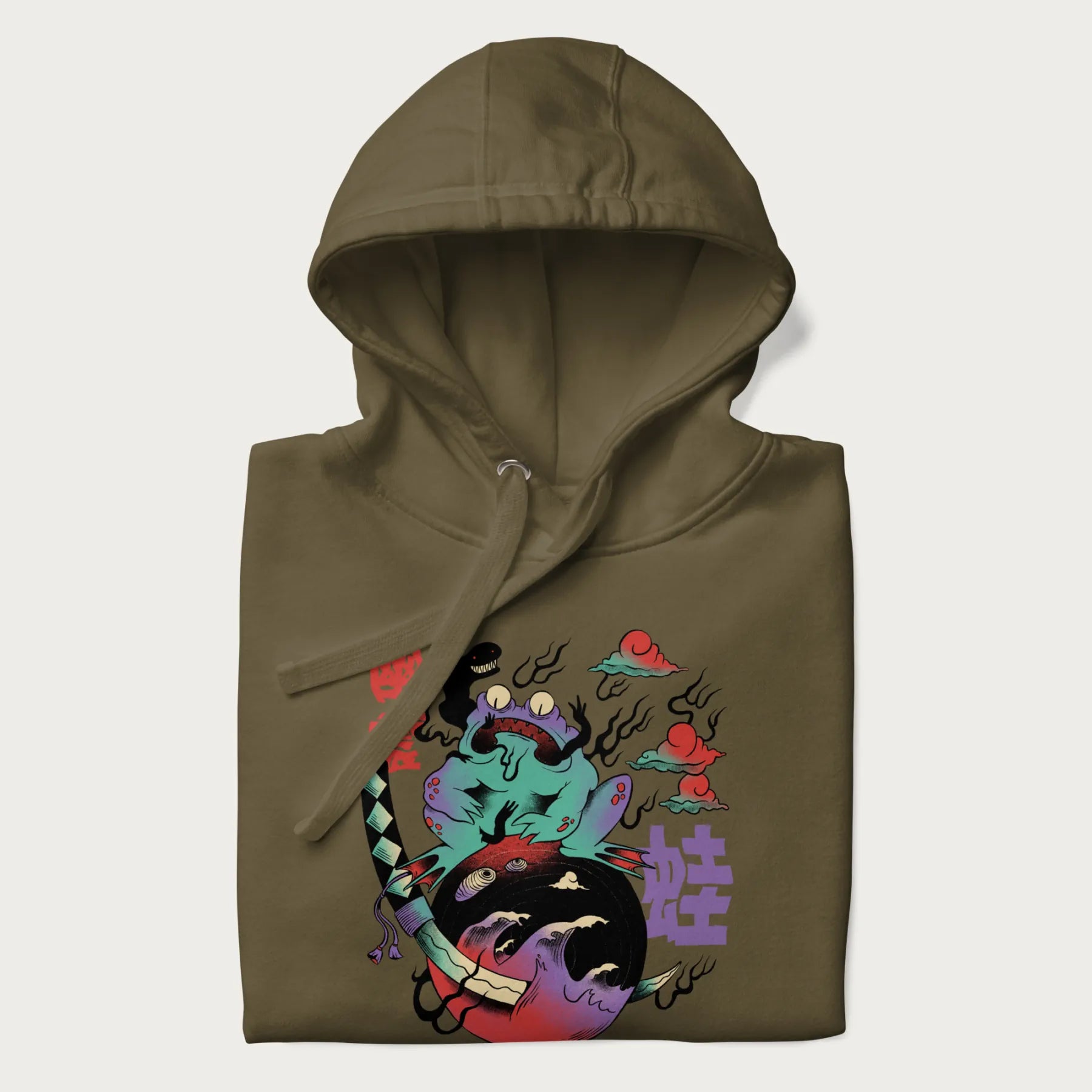 Folded military green hoodie with Japanese psychedelic graphic of a frog with text '蛙' (Frog) and '幽靈' (Ghost) in Japanese characters.