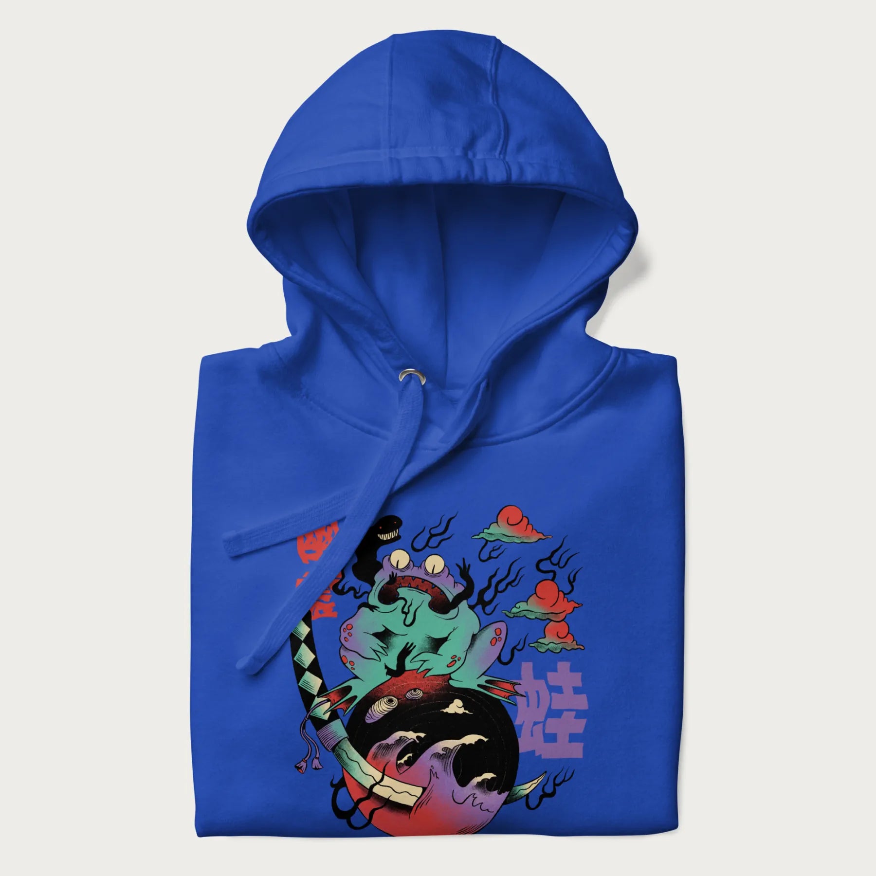 Folded royal blue hoodie with Japanese psychedelic graphic of a frog with text '蛙' (Frog) and '幽靈' (Ghost) in Japanese characters.