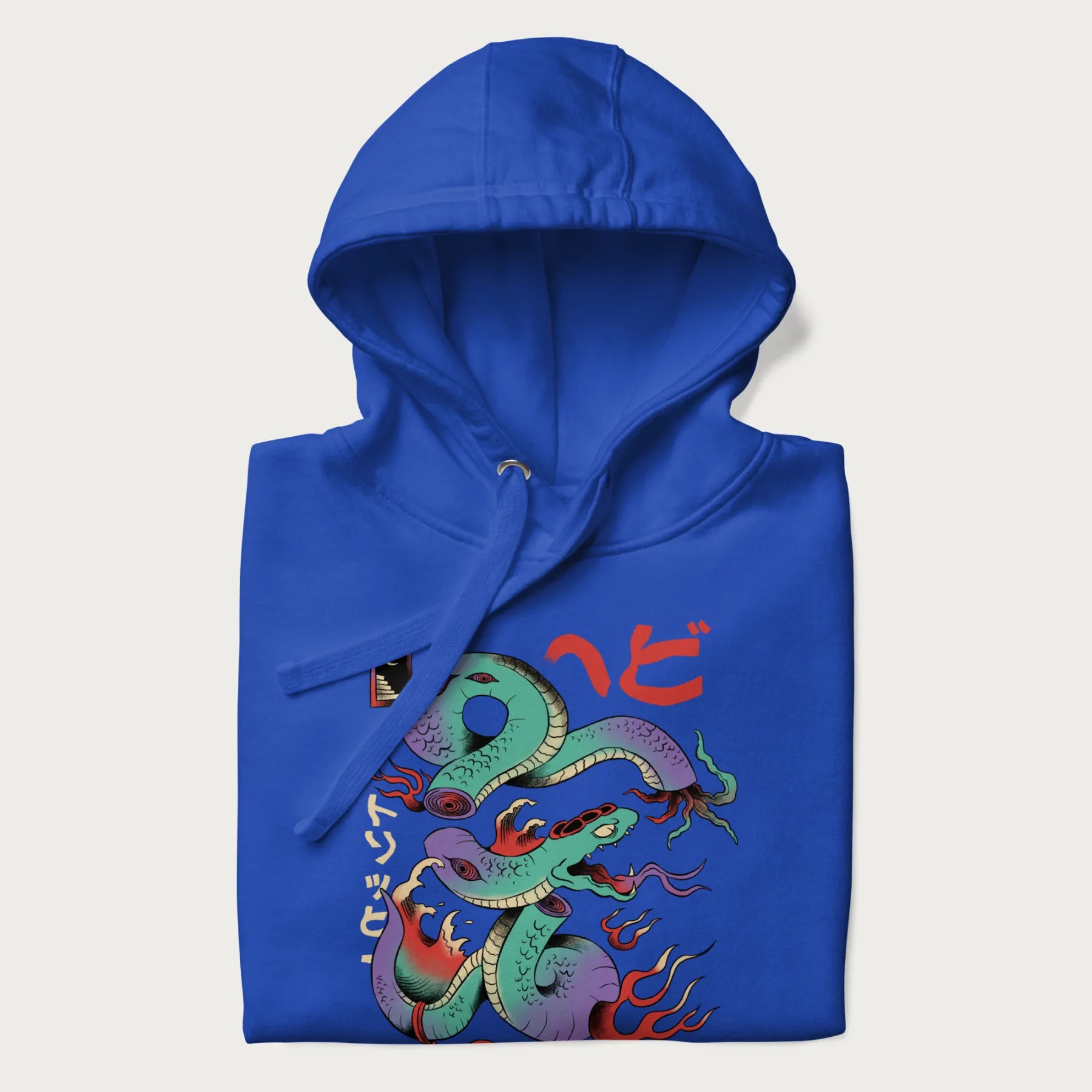 Folded royal blue hoodie with Japanese psychedelic snake graphic, with Japanese text 'ヘビ' (Snake) and 'トリッピー' (Trippy) in vibrant colors.