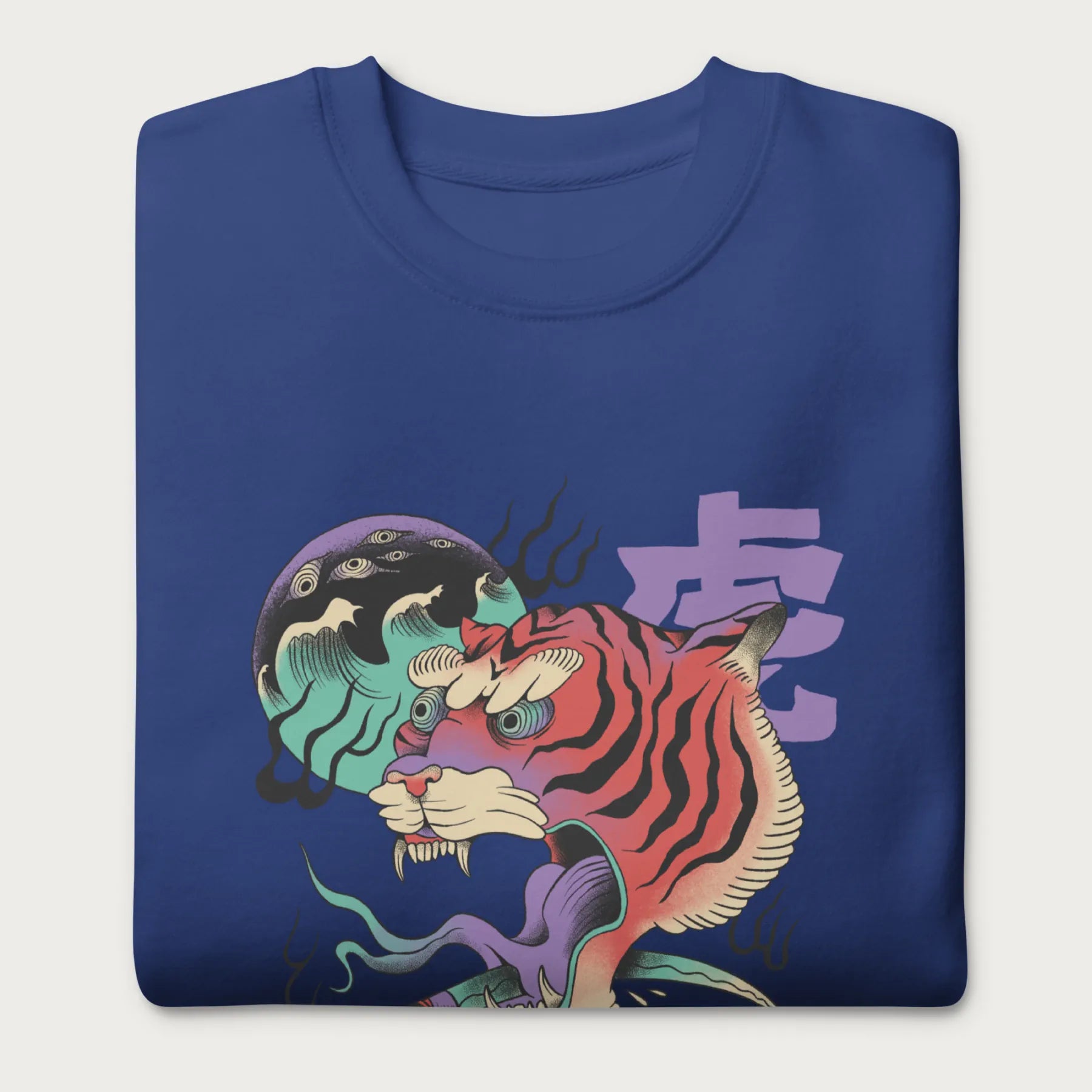 Folded royal blue sweatshirt with a psychedelic Japanese tiger graphic featuring vibrant colors and bold details, including Japanese characters.