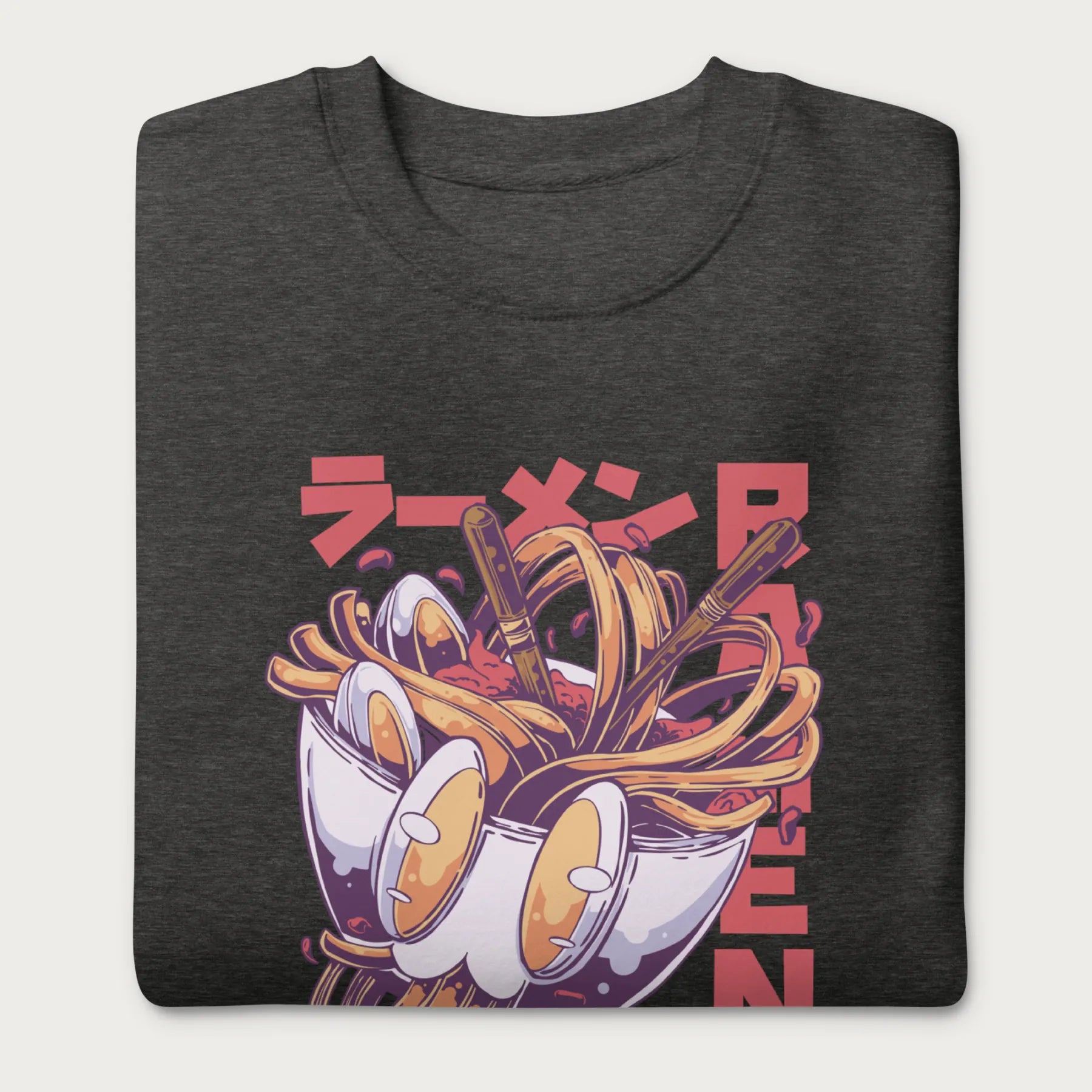 Folded dark grey sweatshirt with a vibrant graphic of a bowl of ramen noodles, depicted in a dynamic, cartoonish style with bold Japanese text.