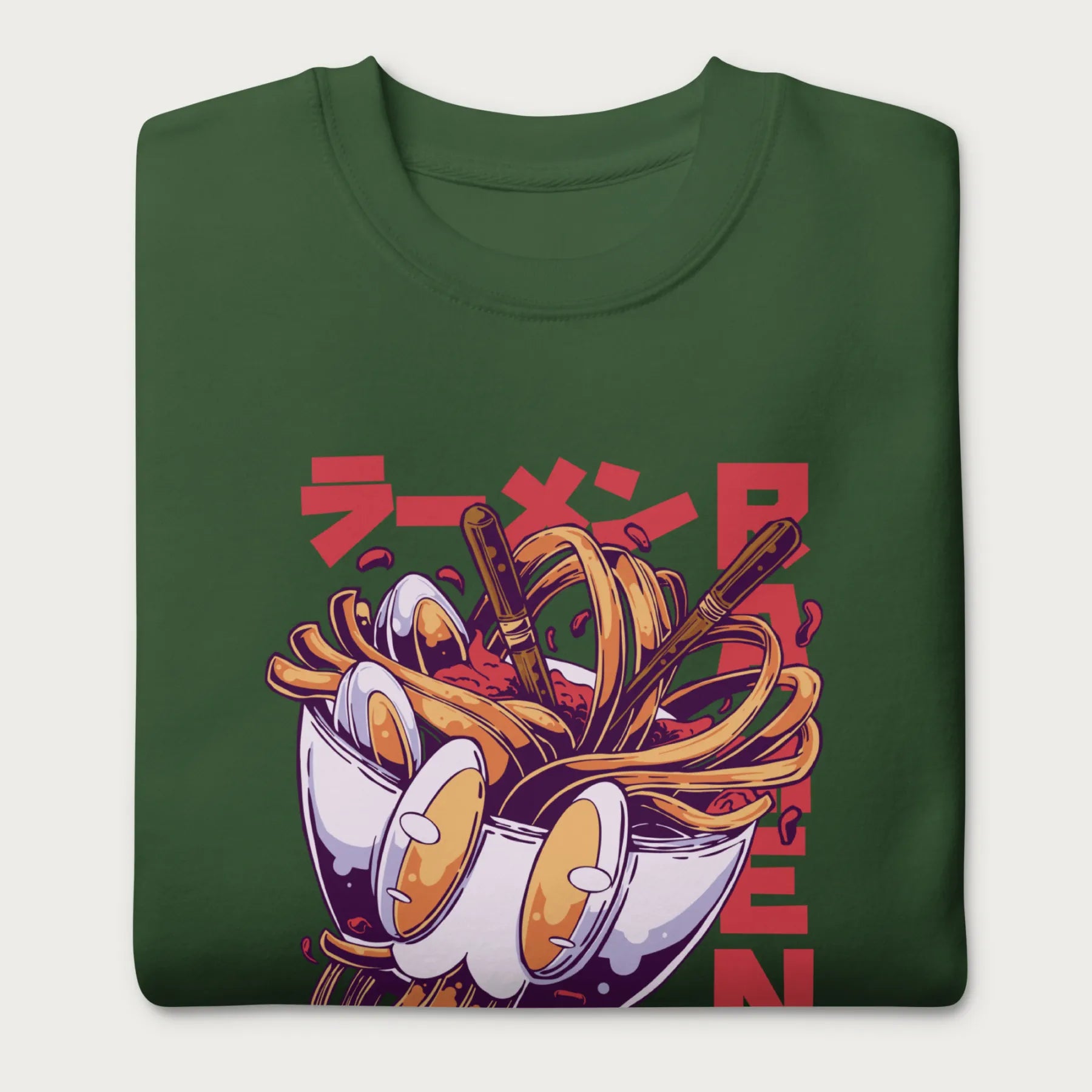 Folded forest green sweatshirt with a vibrant graphic of a bowl of ramen noodles, depicted in a dynamic, cartoonish style with bold Japanese text.