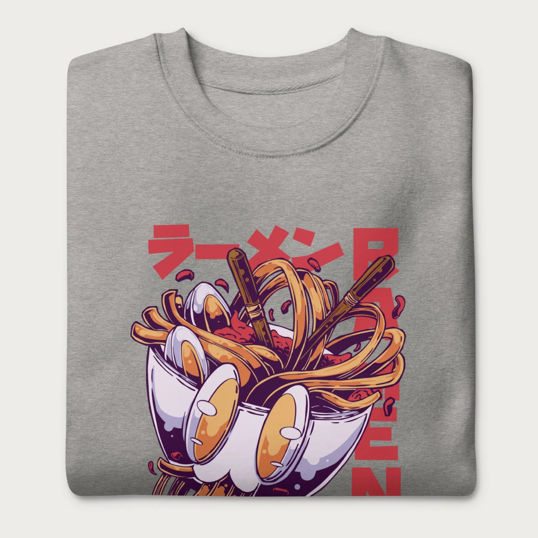 Folded light grey sweatshirt with a vibrant graphic of a bowl of ramen noodles, depicted in a dynamic, cartoonish style with bold Japanese text.