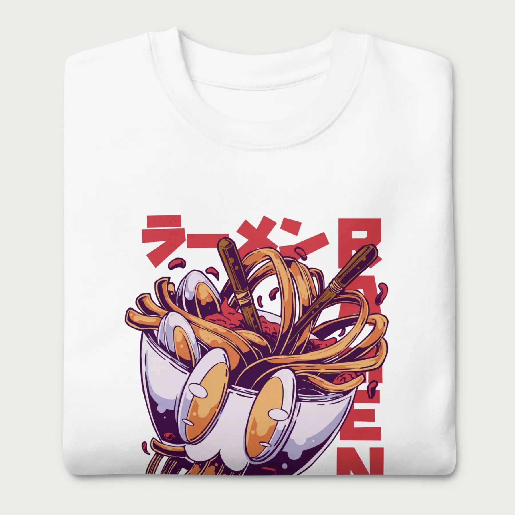 Folded white sweatshirt with a vibrant graphic of a bowl of ramen noodles, depicted in a dynamic, cartoonish style with bold Japanese text.