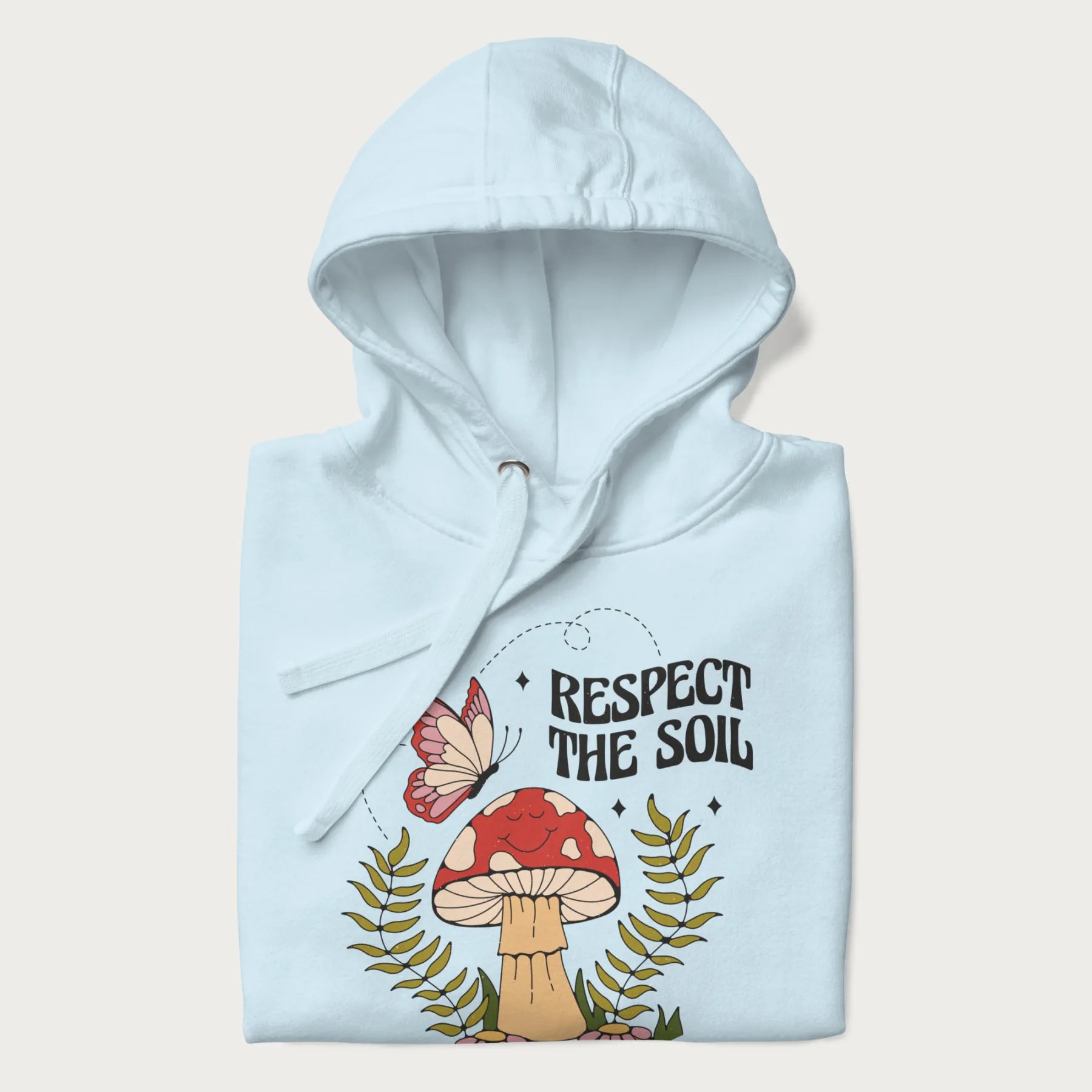 Folded light blue hoodie with mushroom and butterfly design, with the text 'Respect the Soil' above it. 
