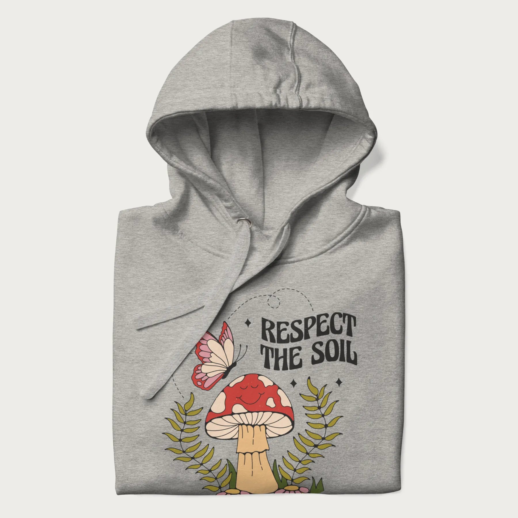 Folded light grey hoodie with mushroom and butterfly design, with the text 'Respect the Soil' above it. 