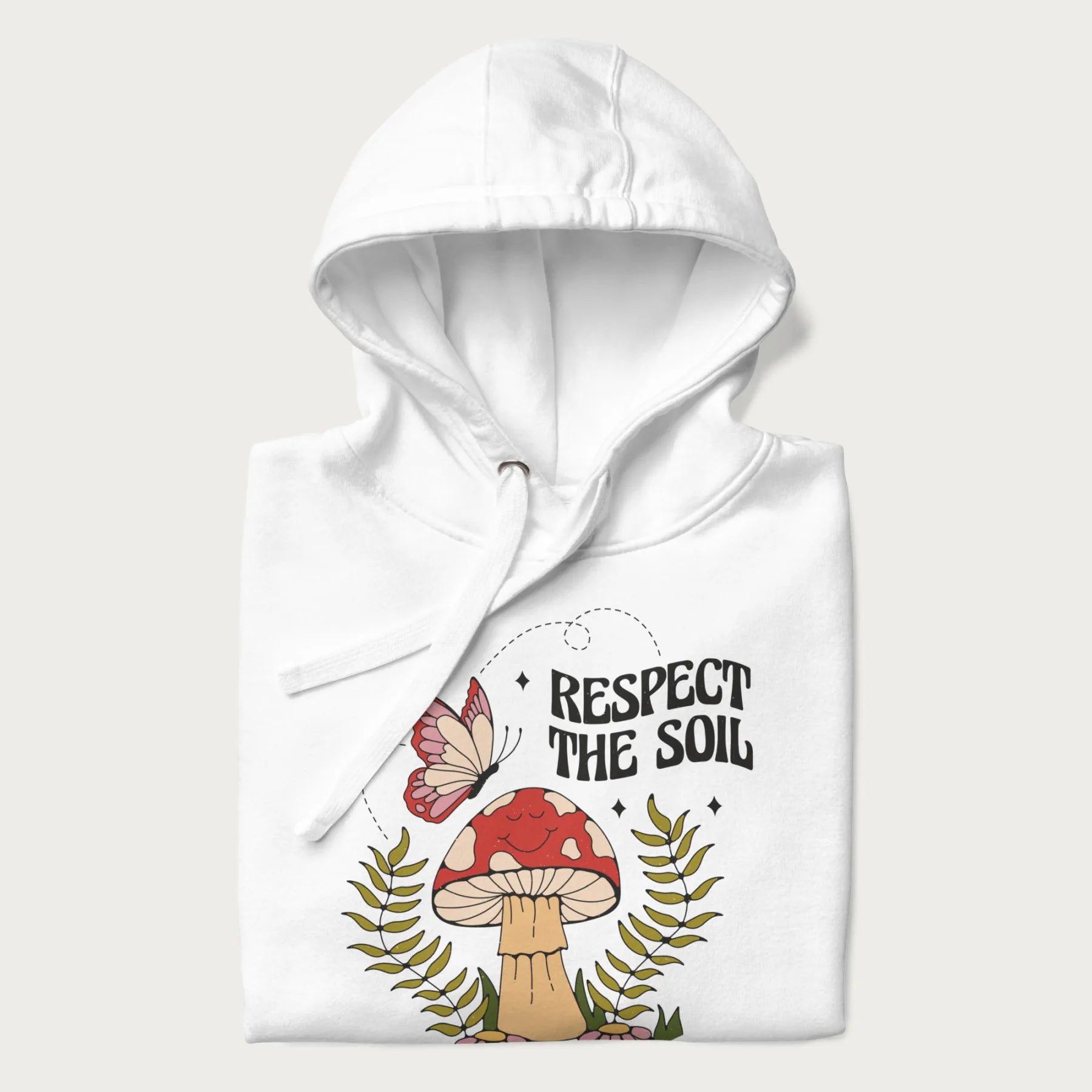 Folded white hoodie with mushroom and butterfly design, with the text 'Respect the Soil' above it. 