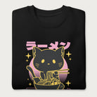 Folded black sweatshirt with Japanese text and a neon outline graphic of a cat eating ramen.