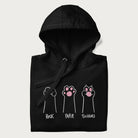 Folded black hoodie with graphic of cat paws playing rock-paper-scissors.