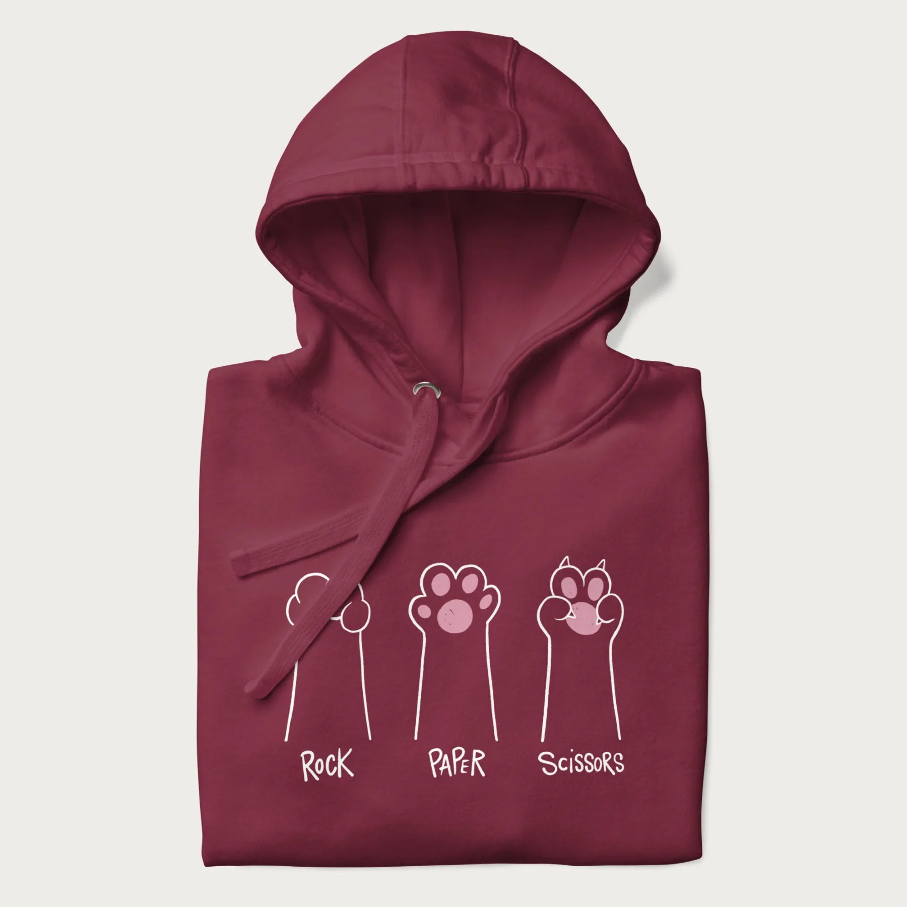 Folded maroon hoodie with graphic of cat paws playing rock-paper-scissors.