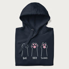 Folded navy blue hoodie with graphic of cat paws playing rock-paper-scissors.
