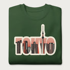 Folded forest green sweatshirt with a graphic of Tokyo's skyline integrated within the letters spelling "TOKYO."