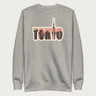 Folded light grey sweatshirt with a graphic of Tokyo's skyline integrated within the letters spelling "TOKYO."