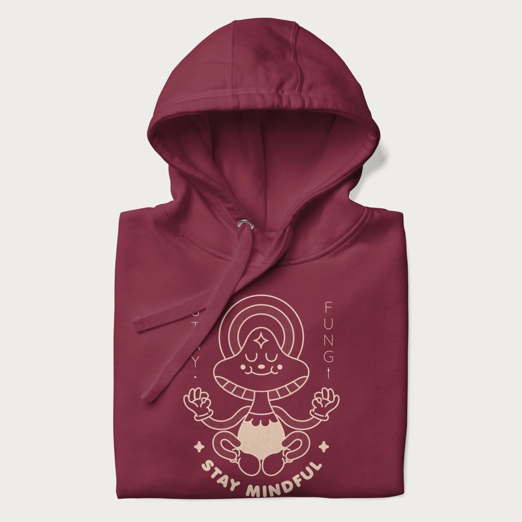 Folded maroon hoodie with a graphic of a meditating mushroom character and the words 'Stay Fungi' and 'Stay Mindful'.