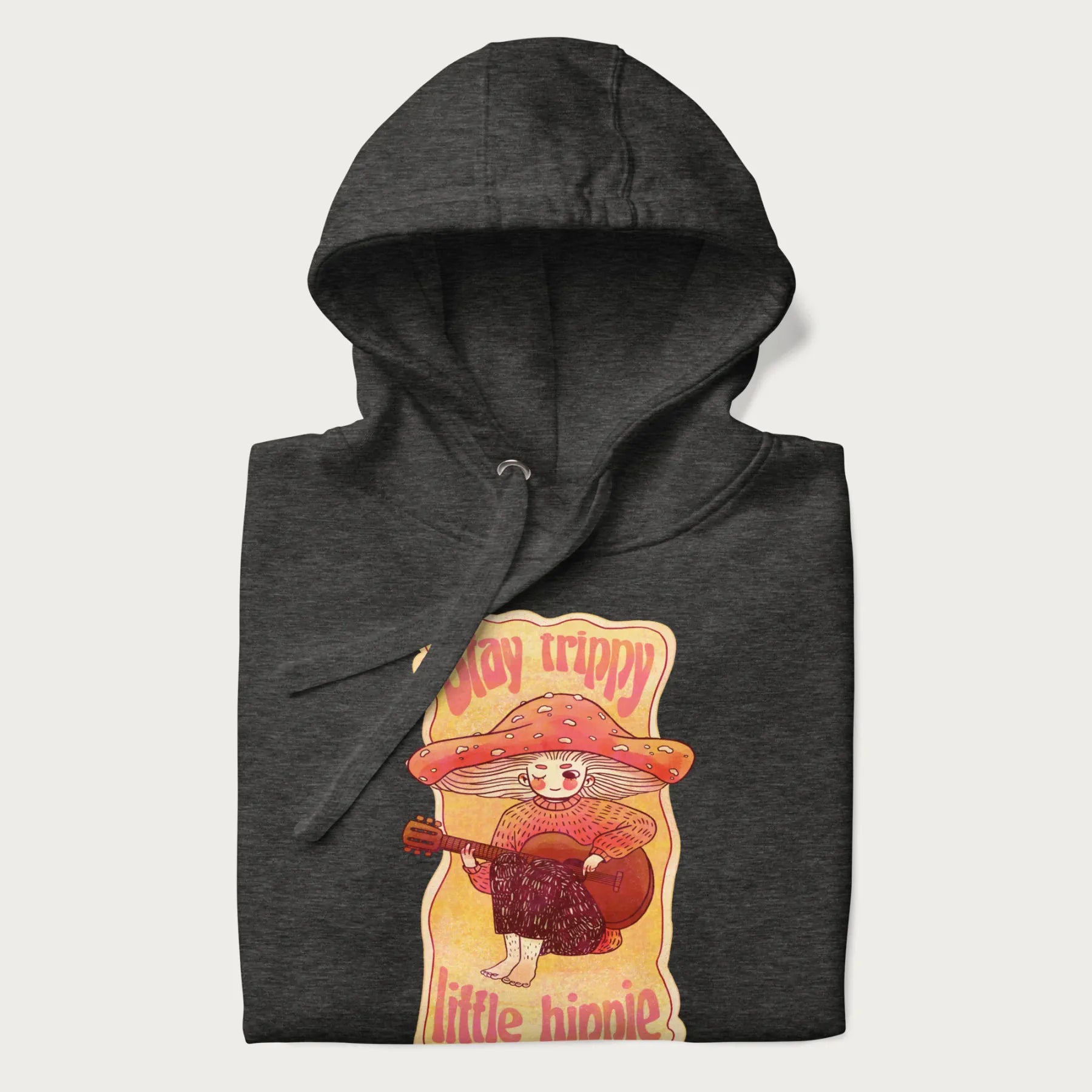 Folded dark grey hoodie with a graphic of a character with a mushroom cap playing a guitar and the text 'Stay Trippy Little Hippie.'