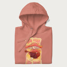 Folded light pink hoodie with a graphic of a character with a mushroom cap playing a guitar and the text 'Stay Trippy Little Hippie.'