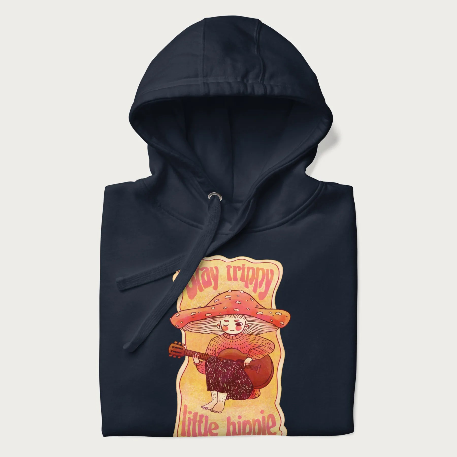 Folded navy blue hoodie with a graphic of a character with a mushroom cap playing a guitar and the text 'Stay Trippy Little Hippie.'