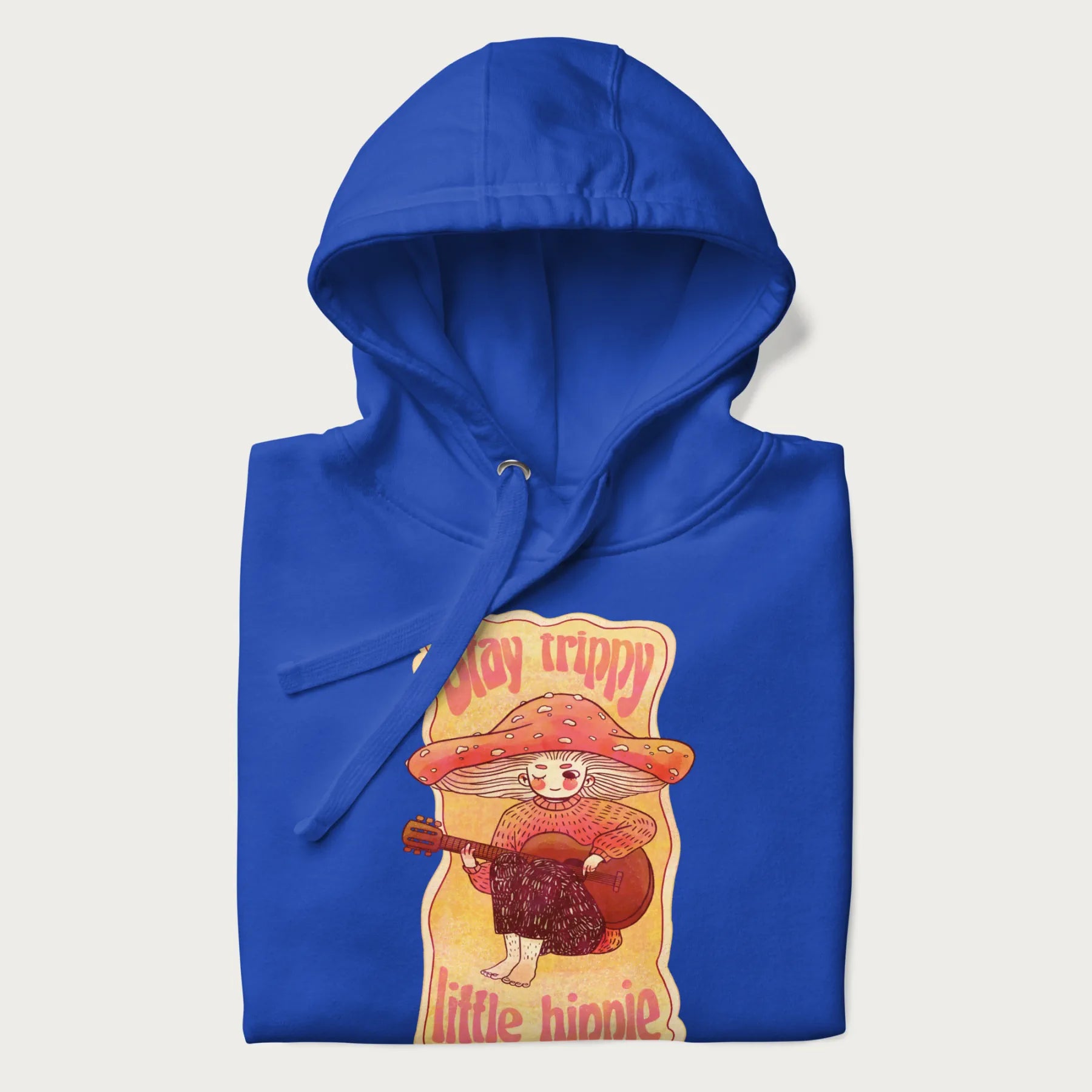 Folded royal blue hoodie with a graphic of a character with a mushroom cap playing a guitar and the text 'Stay Trippy Little Hippie.'