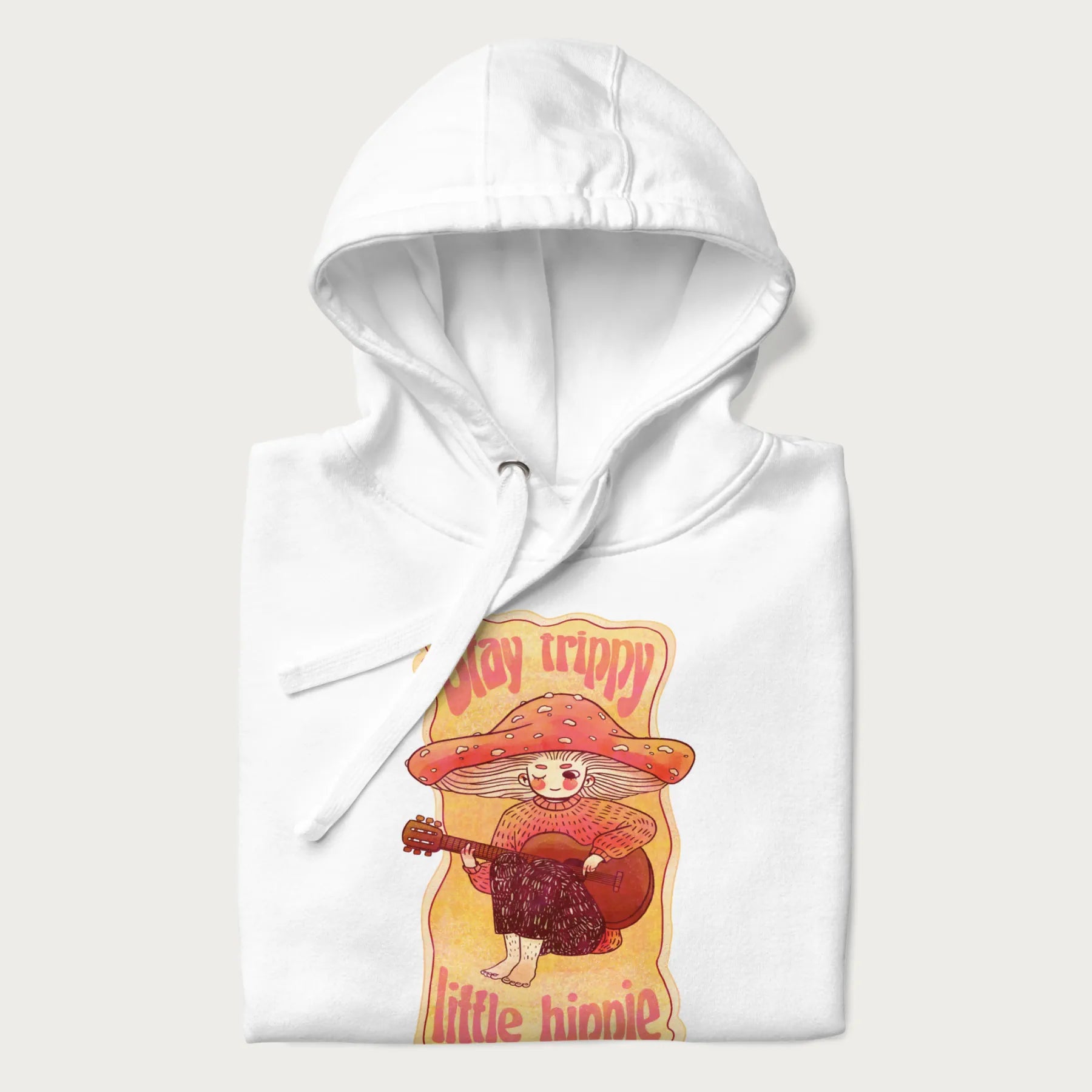 Folded white hoodie with a graphic of a character with a mushroom cap playing a guitar and the text 'Stay Trippy Little Hippie.'