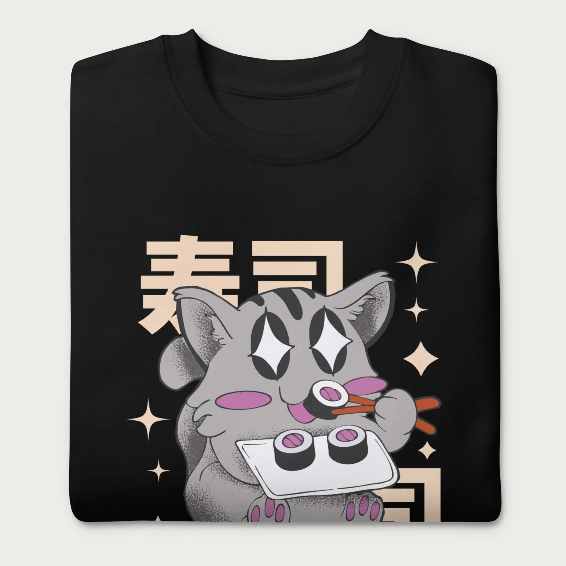 Folded black sweatshirt with Japanese text and a kawaii graphic of a cat eating sushi.