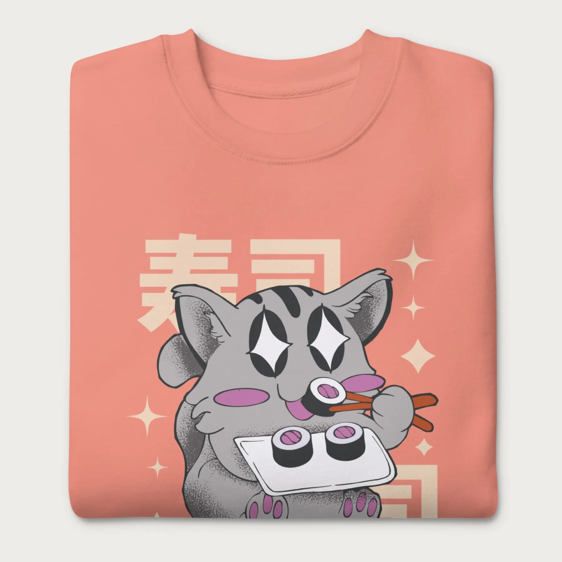 Folded light pink sweatshirt with Japanese text and a kawaii graphic of a cat eating sushi.