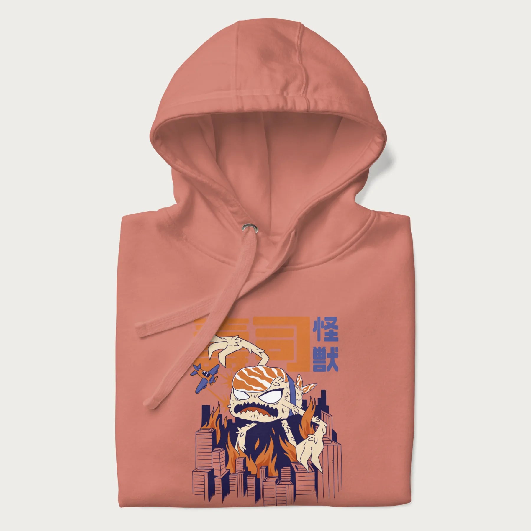 Folded light pink hoodie with Japanese graphic of a sushi monster over a burning city with Japanese text.