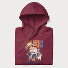 Folded maroon hoodie with Japanese graphic of a sushi monster over a burning city with Japanese text.