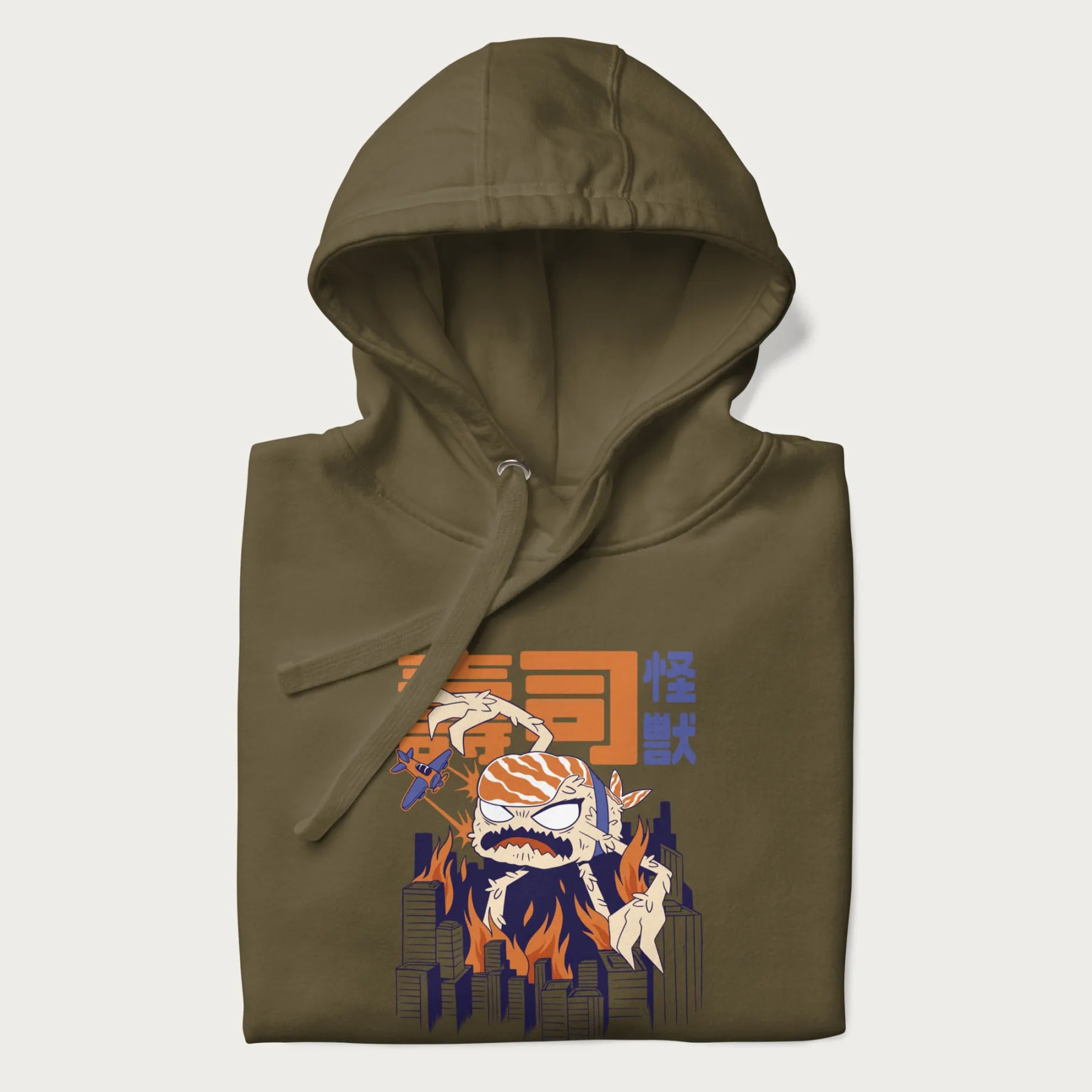 Folded military green hoodie with Japanese graphic of a sushi monster over a burning city with Japanese text.