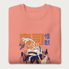 Folded light pink sweatshirt with a graphic of a monstrous sushi roll attacking a city and Japanese text.