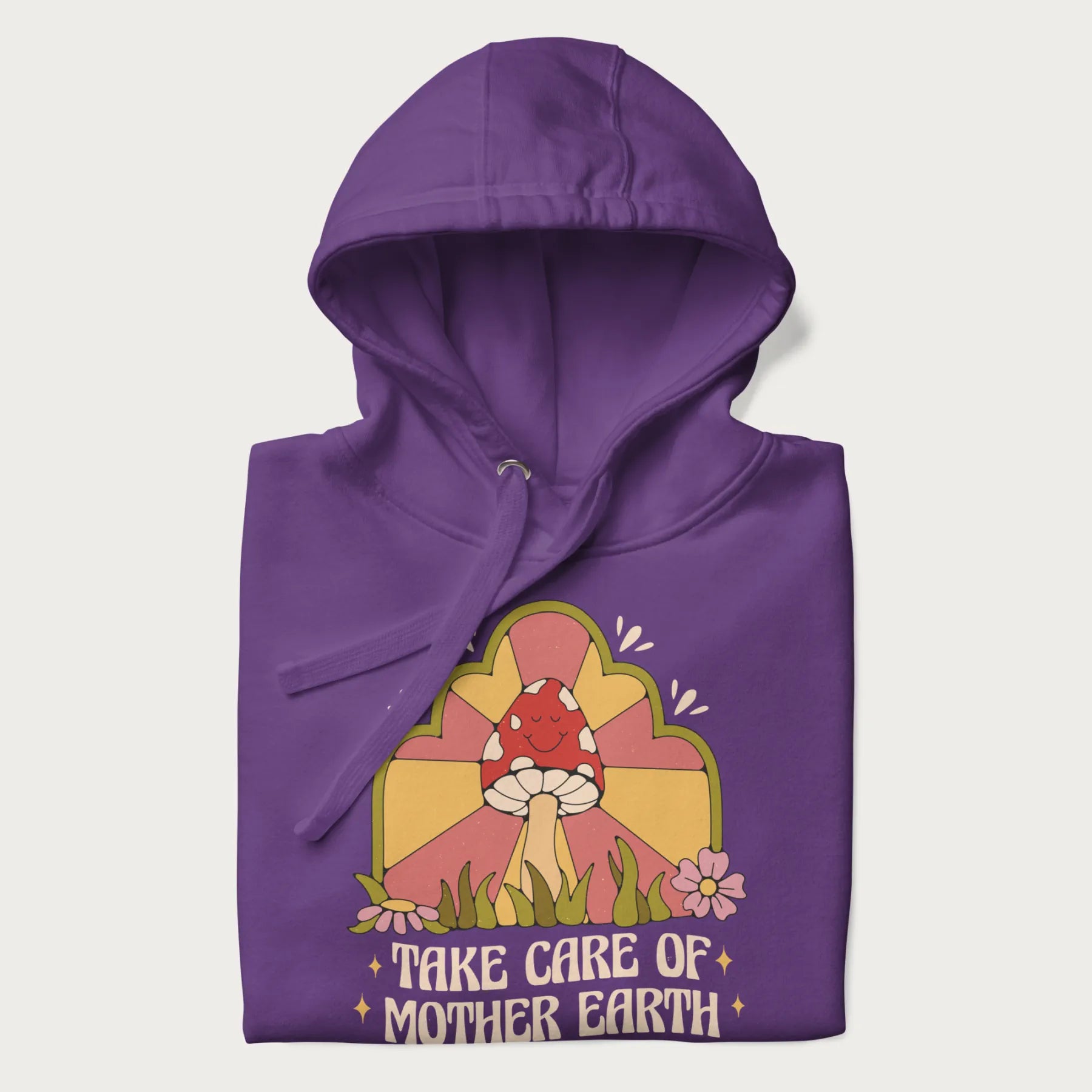 Folded purple hoodie with a graphic of a happy red mushroom, sunburst background, and the text 'Take Care of Mother Earth'.