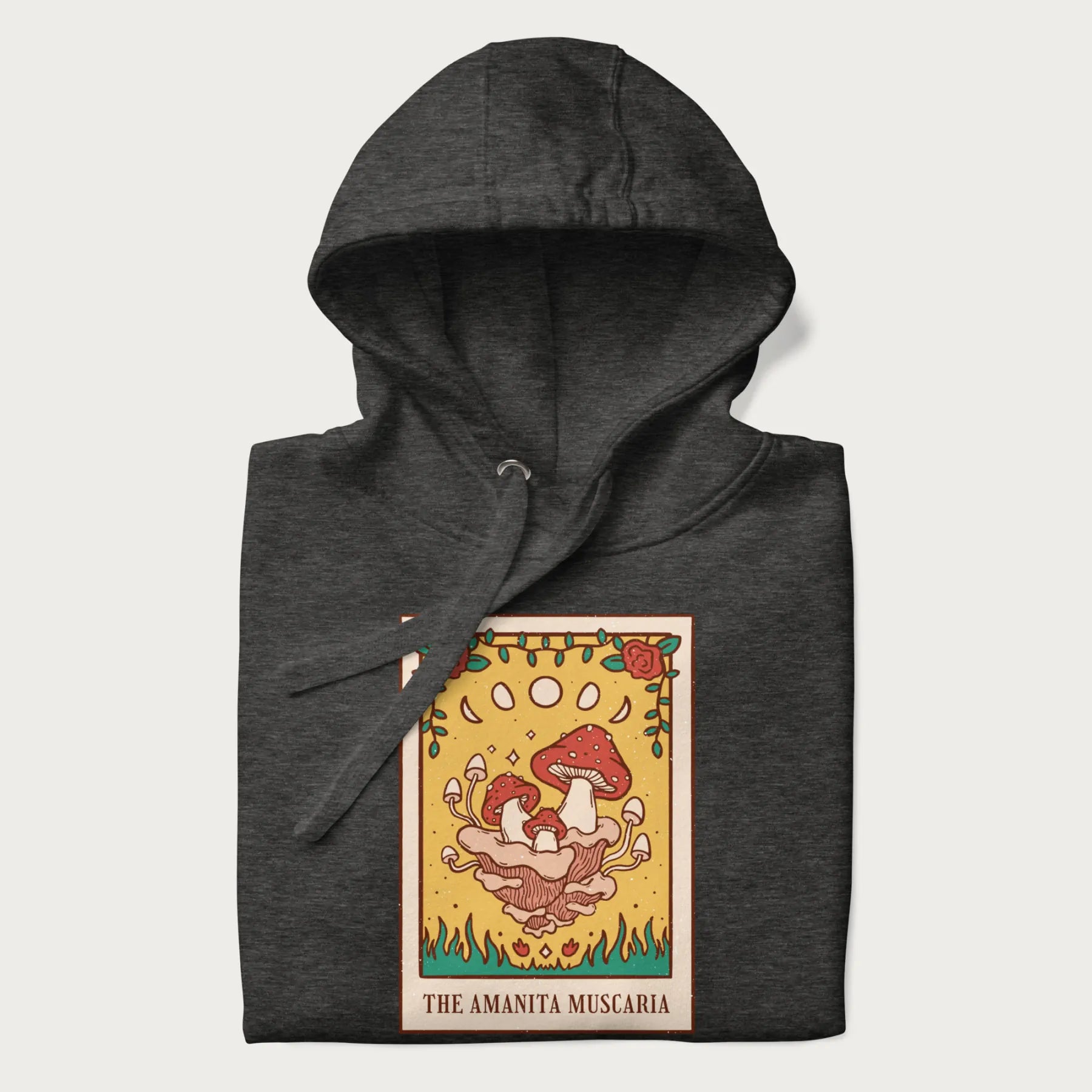 Folded dark grey hoodie featuring a graphic of Amanita Muscaria mushrooms with floral accents and moon phases, resembling a tarot card.