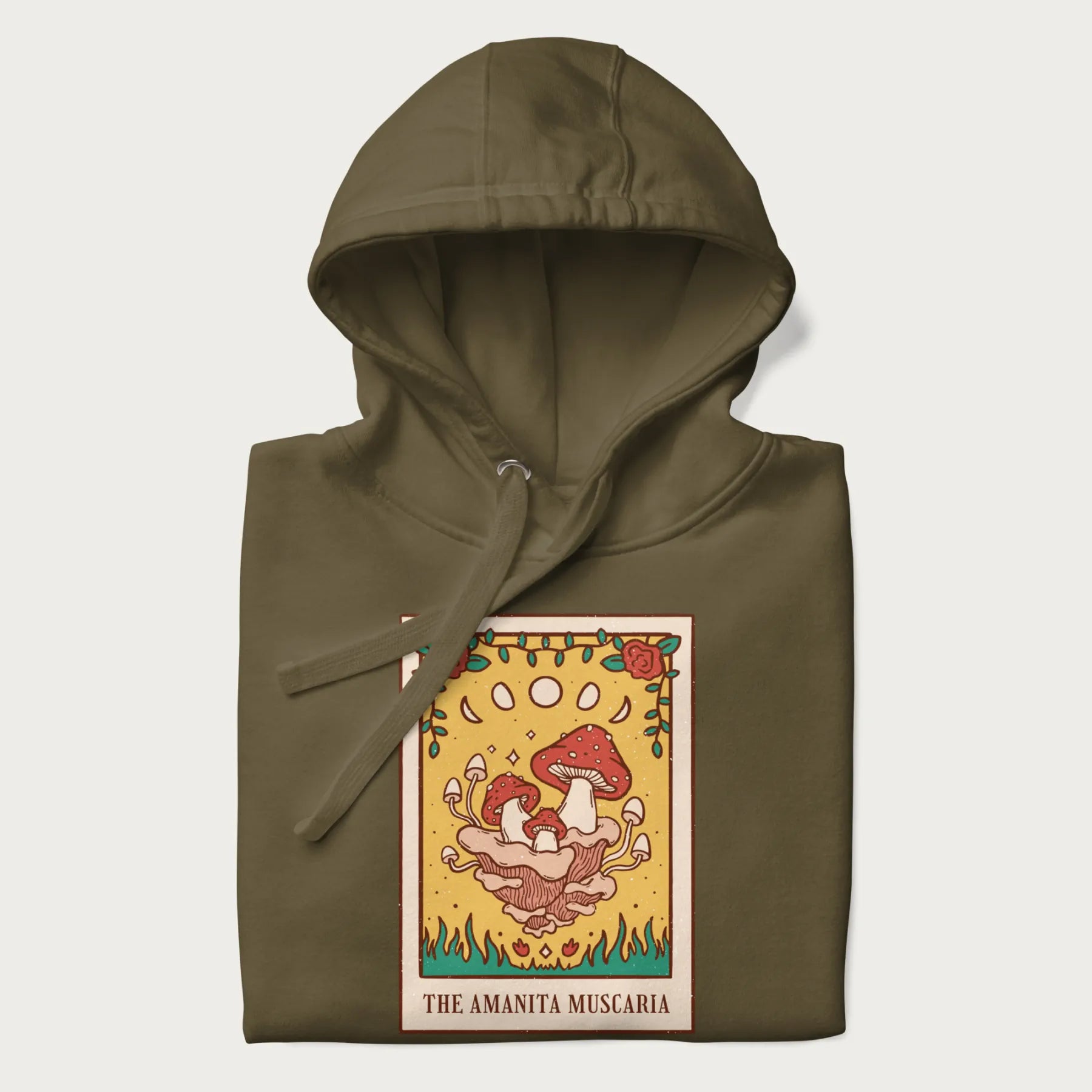 Folded military green hoodie featuring a graphic of Amanita Muscaria mushrooms with floral accents and moon phases, resembling a tarot card.