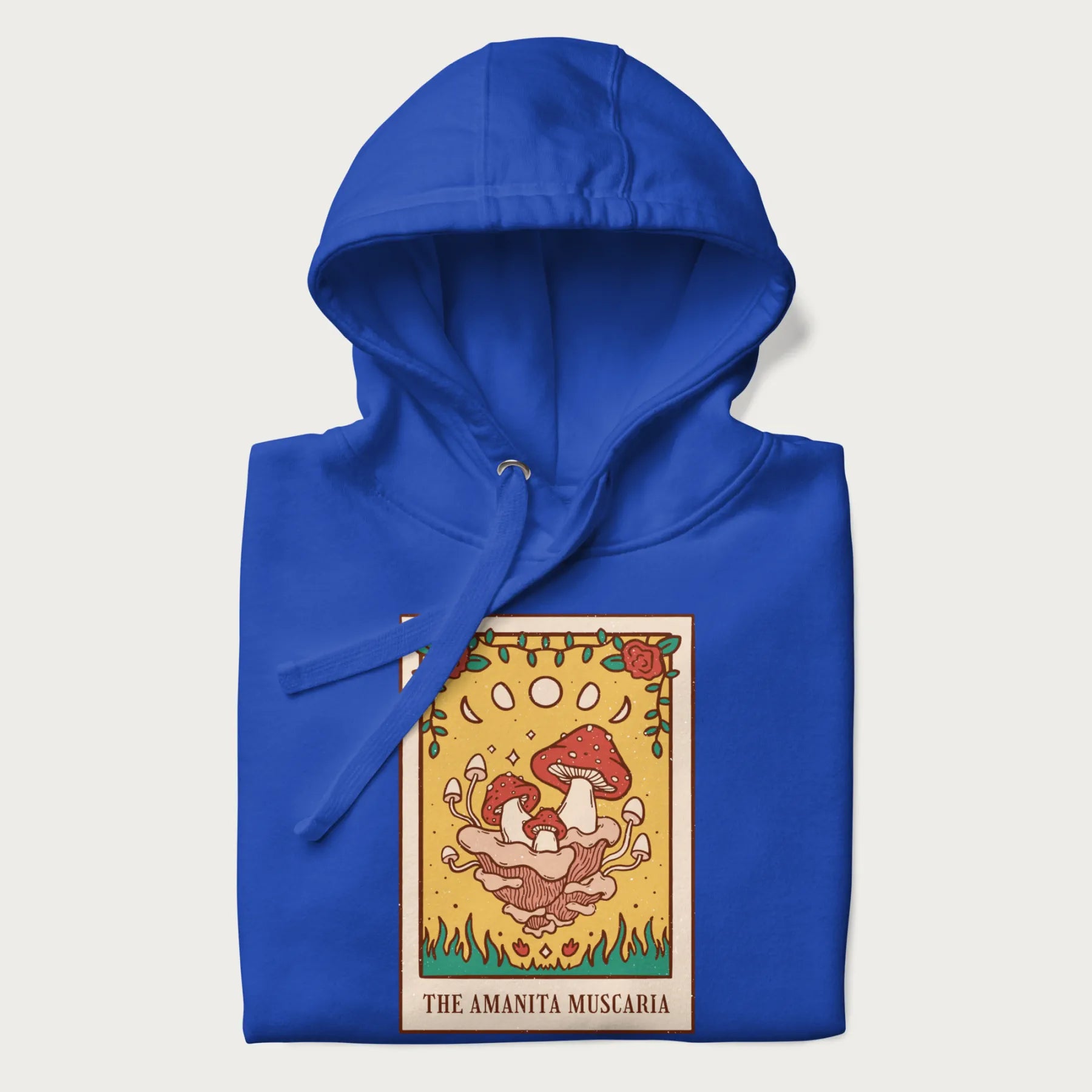 Folded royal blue hoodie featuring a graphic of Amanita Muscaria mushrooms with floral accents and moon phases, resembling a tarot card.