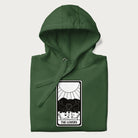 Folded forest green hoodie with a 'The Lovers' tarot card graphic of two cats with intertwined tails forming a heart, wine, and roses.