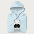 Folded light blue hoodie with a 'The Lovers' tarot card graphic of two cats with intertwined tails forming a heart, wine, and roses.